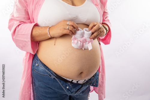 Pregnant big belly mother holding knitted little shoes