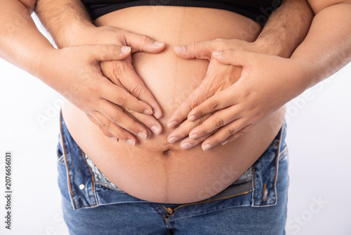 Pregnant big belly parents holding the baby making a heart shape with hands