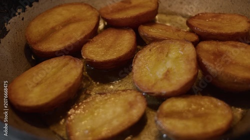 Potatoes cut in half, fried in oil in a pan
