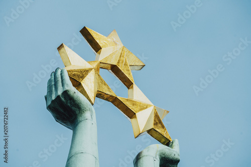 Fotografie View of the golden stars held aloft by the statue at the top of the Freedom Monument against a clear blue sky in Riga, Latvia