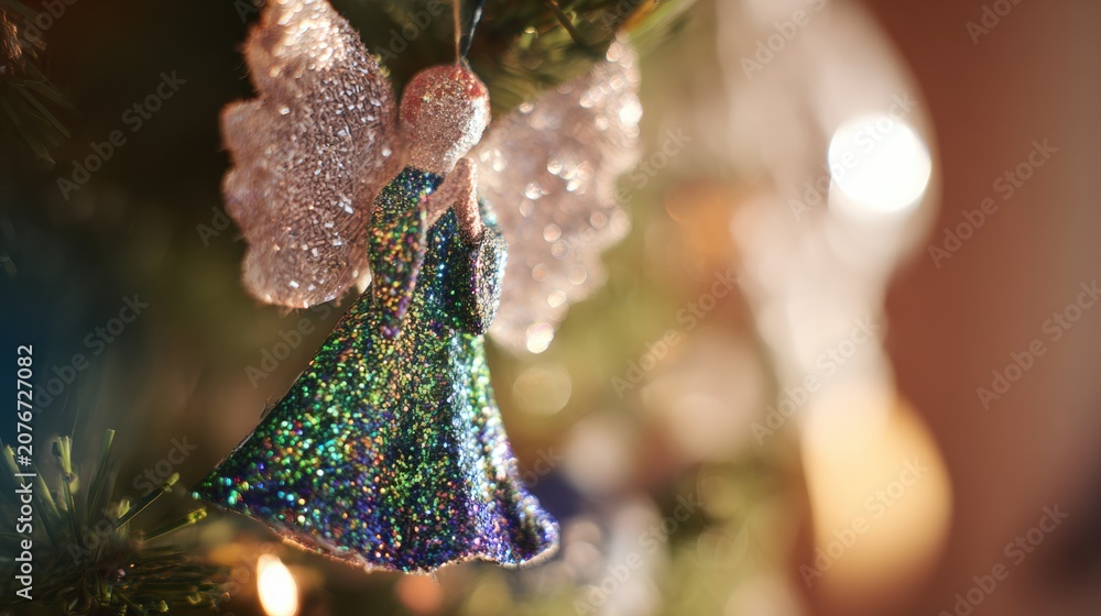 Fototapeta premium Sparkling angel ornament hanging on a Christmas tree with blurred decorations in the background