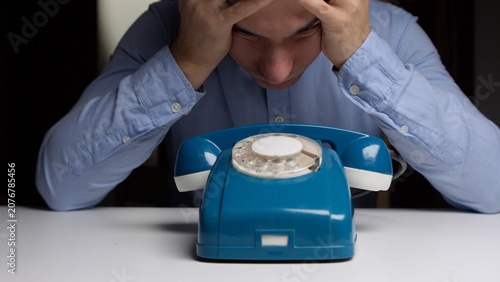 Fotografie Stressed man sitting at a desk with his hands on his head, anxiously waiting for