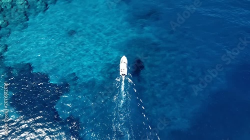 Top down view of white boat in deep blue water.