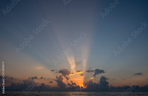 Photography Sun setting behind dark clouds with dramatic golden crepuscular light rays