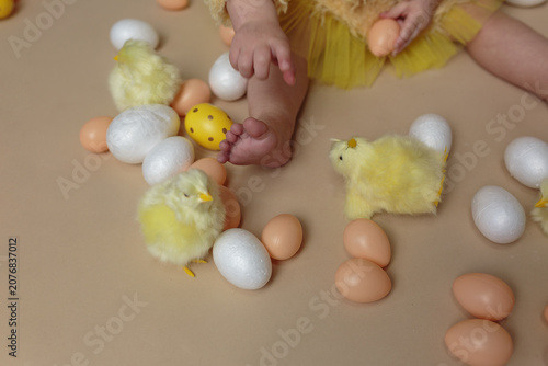 Baby's feet and hands playing with Easter eggs and chicks on the floor