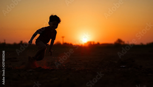 Silhouette of a Happy Young Boy Running at Sunset in an Open Field
