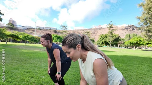 A couple of female friends warming up before a workout in a park