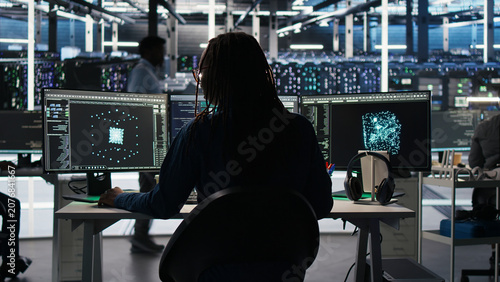 Fotografía Server room software programmer interpreting AI generated data analytics graphs, wearing headphones, while operates AI tool showing system metrics, listening music