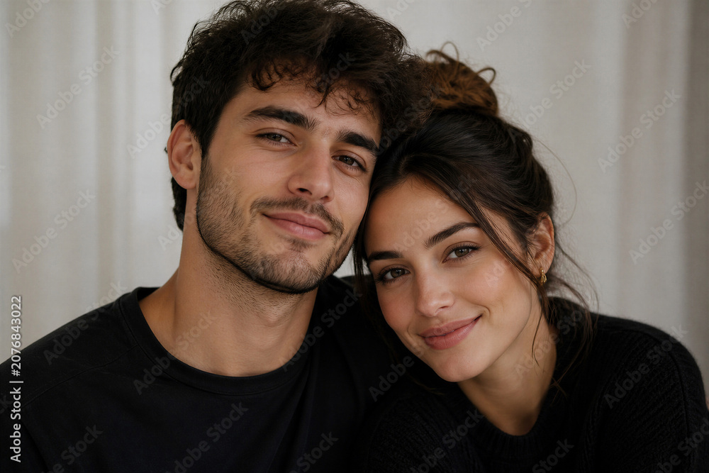 Obraz premium Young couple posing closely smiling in neutral indoor setting