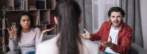 Foto Worried Young Black Woman And Young Caucasian Man Expressing Frustration While Arguing In Living Room, Discussing Personal Issues Together In Emotional Situation, Concept Of Conflict Resolution