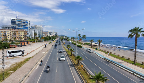 Quadro su tela Coastal road in Alanya, Turkey with palm trees and vehicles along the beach, mod