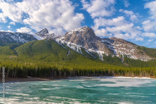 Bright Cloudy Blue Sky Over Mountains By A Frozen Wedge Pond In The Spring