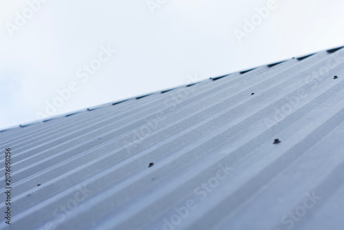 фотографія Corrugated metal roof panel with fastening screws and soft sky background illustrates durable modern cladding