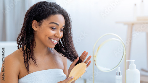 Canvastavla Smiling Young African American Woman Taking Care Of Curly Hair With Brush In Front Of Mirror At Home, Engaged In Daily Beauty Routine