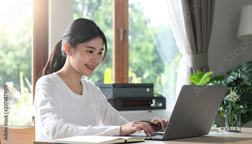 Young asian woman working on laptop at sunny home office, remote education and digital communication, productive lifestyle