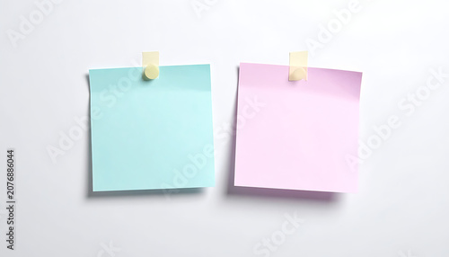 Two square paper sticky notes in pastel blue and pink attached with masking tape
