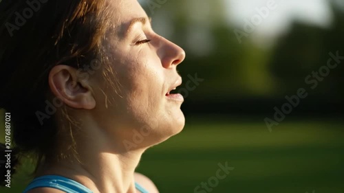 Side profile of woman with closed eyes in sunshine.