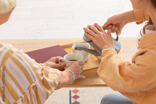 Young woman pouring tea for...