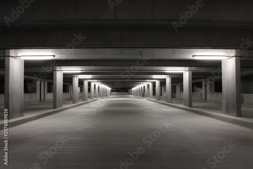 Underground parking structure showing concrete pillars and lights in a dimly lit environment