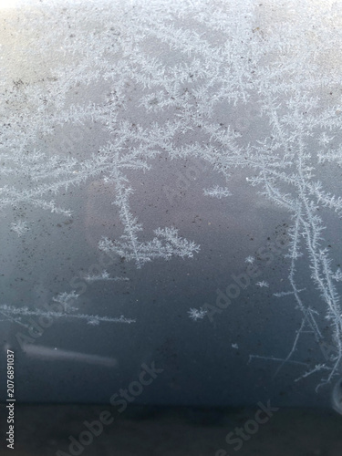 Frost patterns on window glass on a snowy day, winter texture background