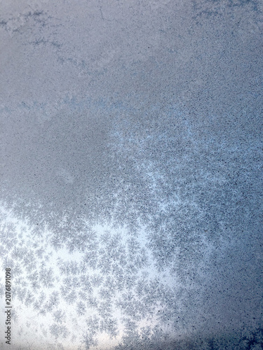 Frost patterns on window glass on a snowy day, winter texture background