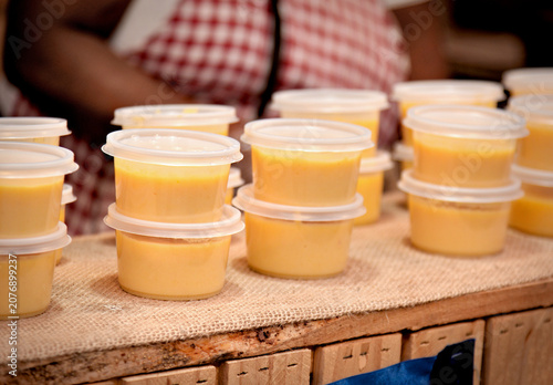Curau (traditional Brazilian sweet corn pudding) in individual plastic containers, at a Festa Junina stall. Close-up image.