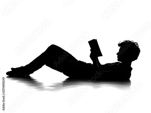 Silhouette of a person reading a book while lying down.