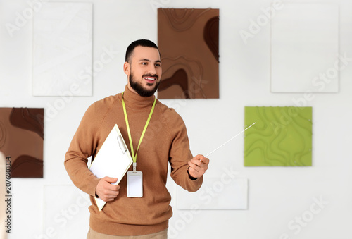 Male guide near paintings at exhibition in art gallery