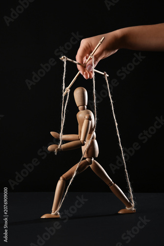 Obraz na plátně Hand of puppeteer manipulating marionette on black background