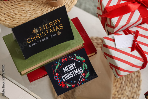 Books with greeting cards and Christmas presents on table in room, top view