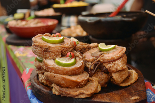 Traditional Brazilian Crispy Rolled Pork Belly Bites served with Lime and Chili Pepper on Wooden Board