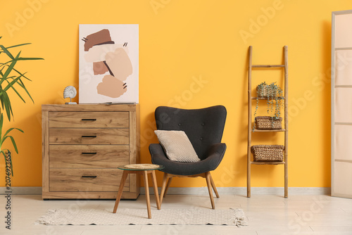 Bild auf Leinwand Interior of stylish room with armchair, commode and houseplants on wooden ladder