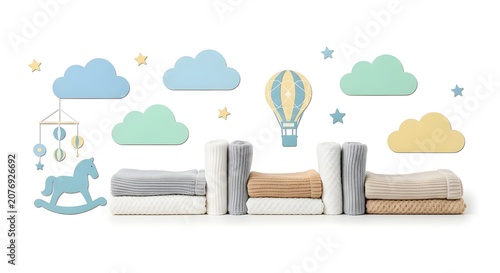 A charming collection of folded baby blankets arranged with whimsical nursery decor including clouds, stars, a hot air balloon, and a rocking horse.