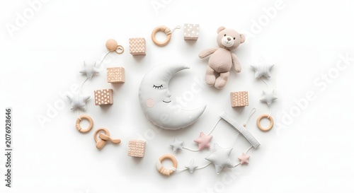 Overhead view of a crescent moon, teddy bear, wooden blocks, and star-shaped baby mobile arranged in a circular pattern on a white background.