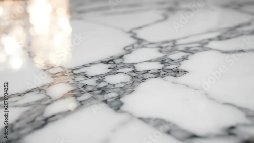 Smooth cinematic tracking shot over luxury statuario white marble surface with elegant gray veins and soft light reflections