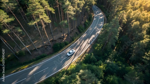 Aerial view of winding forest road with moving car creating abstract natural landscape background in lush green wilderness vector illustration