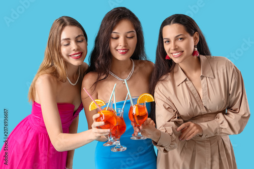 Beautiful young women with aperol spritz cocktail on blue background