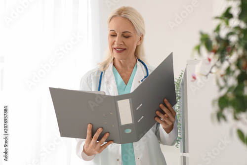 Mature female doctor with folder in clinic
