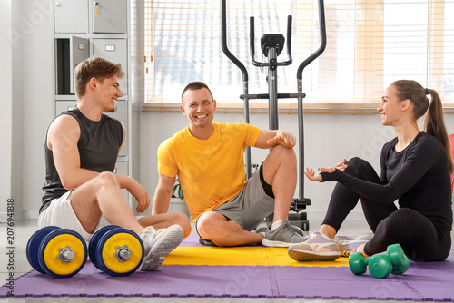 Male coach talking to young people in gym