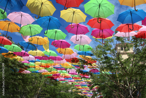 Obraz na plátně Vibrant Canopy of Colorful Umbrellas
Hanging Over Street Under Blue Sky