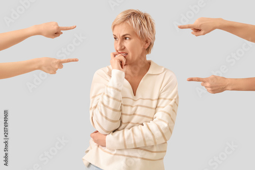 Obraz na plátně People pointing at worried mature woman on light background