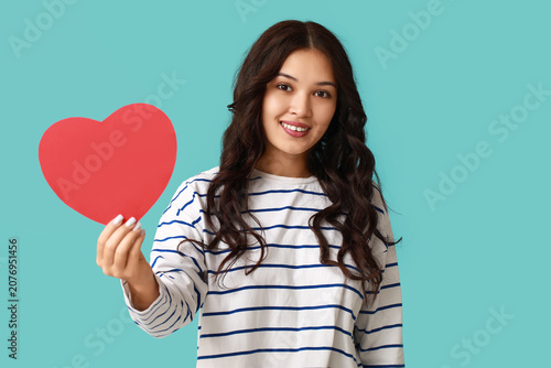 Happy young Asian woman with red paper heart on blue background. Valentines D...