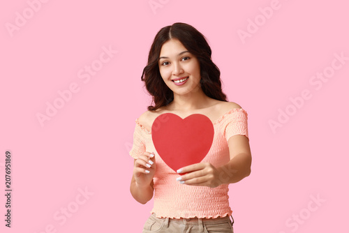 Happy young Asian woman with red paper heart on pink background. Valentines D...