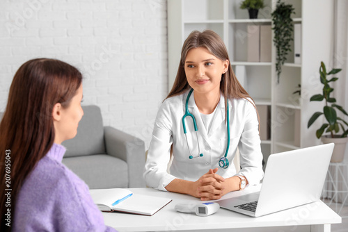 Beautiful doctor working with patient at table in clinic