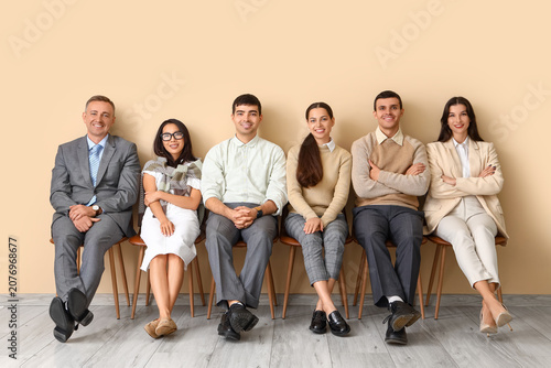 Business people sitting near beige wall