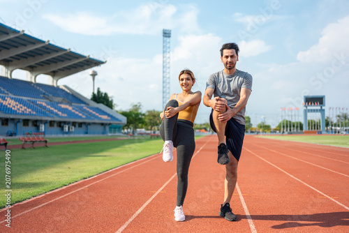 Diverse young man and woman athletes exercising together at stadium.