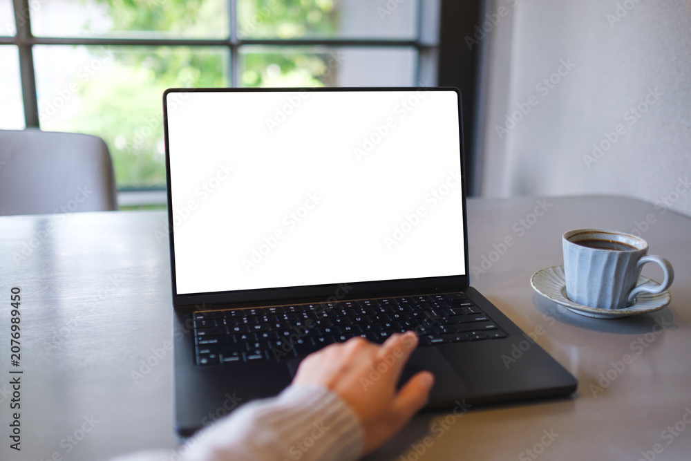 Fototapeta premium Mockup image of a woman working on laptop computer with blank white desktop screen