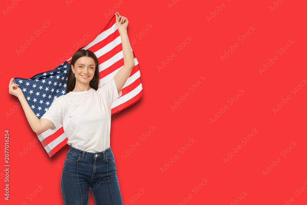 Fototapeta premium Young woman waves American flag proudly. Celebration and patriotism concept