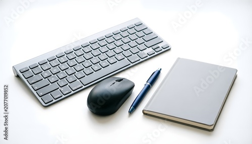 Minimalist computer workspace with wireless keyboard, mouse, pen, and notebook on white background