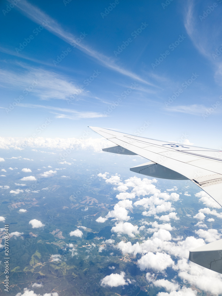 Fototapeta premium View from an airplane window looking out over beautiful clouds and blue sky during flight.